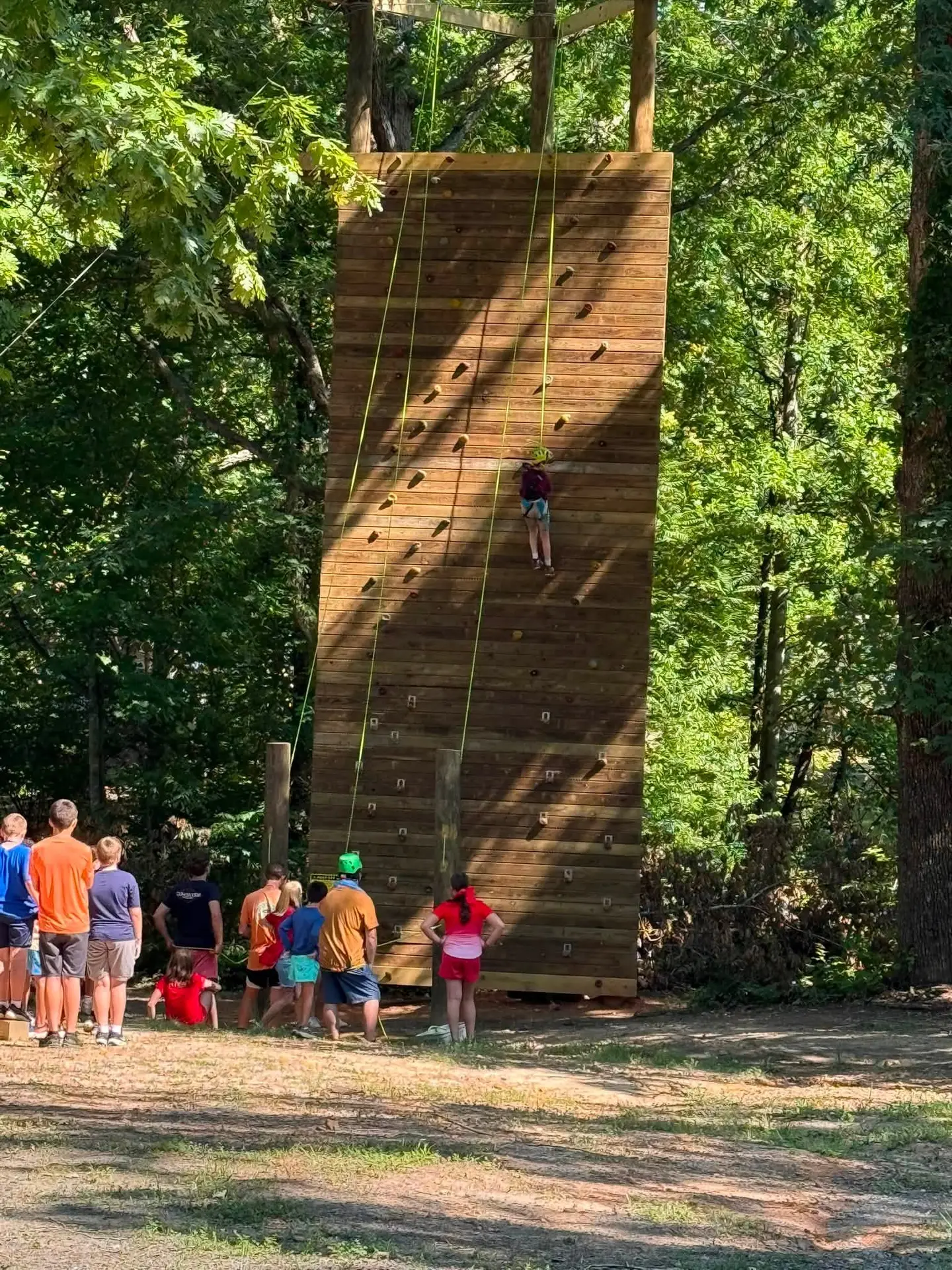 Climbing wall in the woods with campers waiting their turn